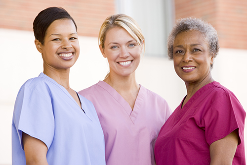 Three young female nurses all wearing different color scrubs